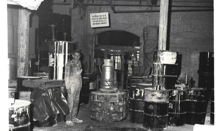 1950s Manufacturing Plant w. Employee Standing and Smiling@2x